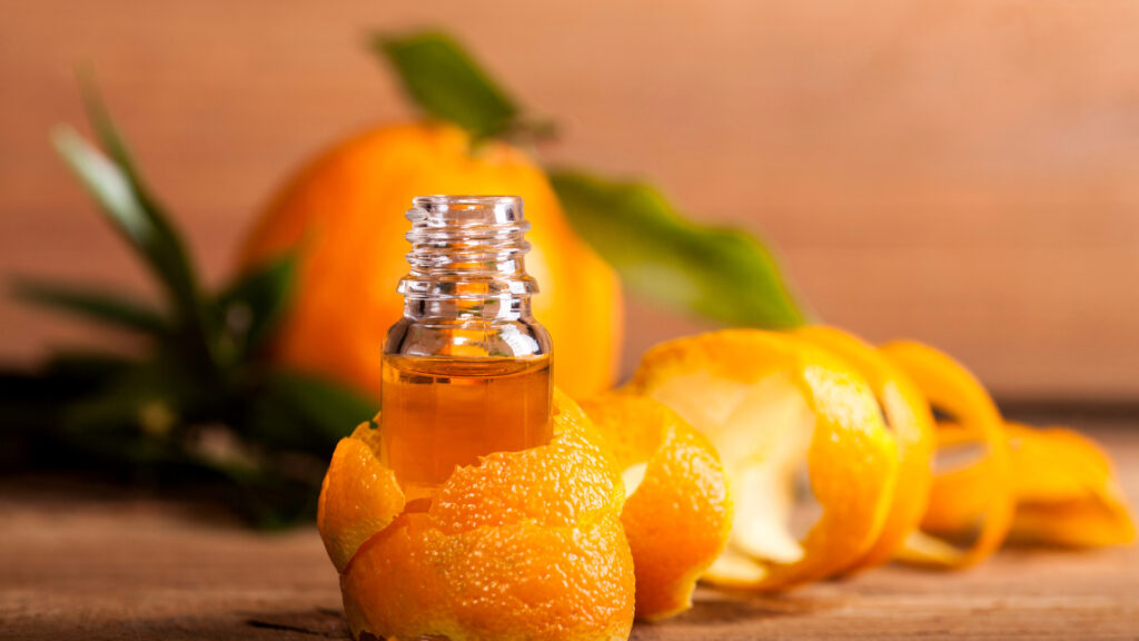 Ätherisches Öl der süssen Orange im Glas mit einer Orangenschale darum gewickelt - Orange süss.